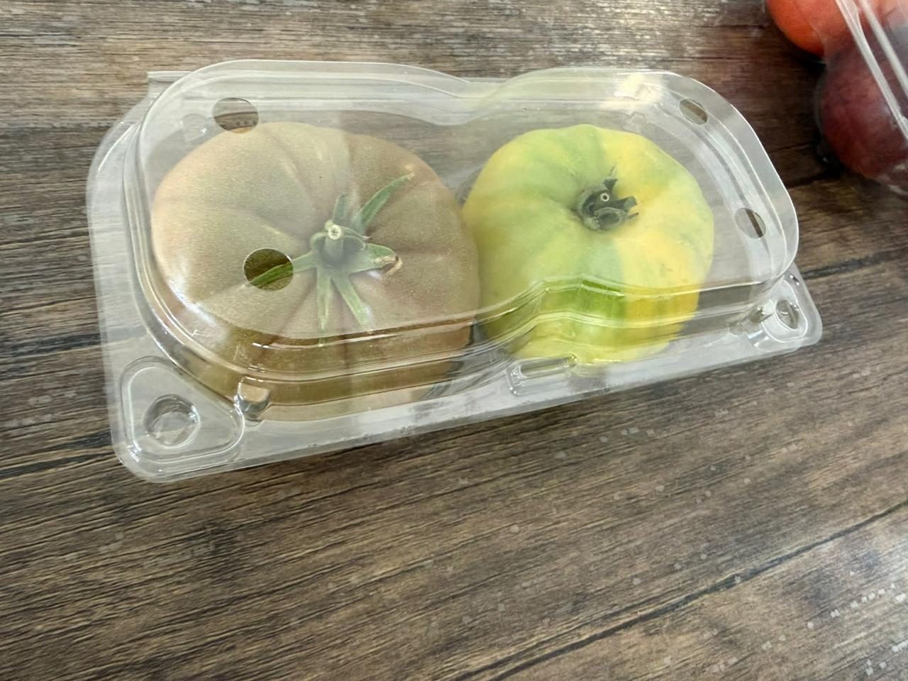 Two heirloom tomatoes in a clamshell